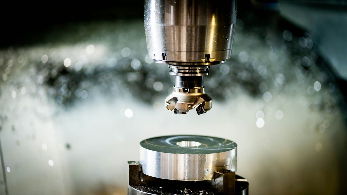 A CNC face mill cutting a steel part through coolant spray