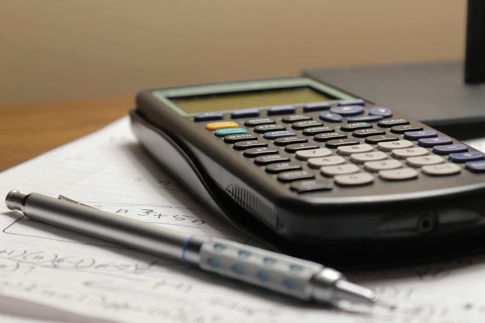 A calculator and a pen on a sheet of handwritten calculations