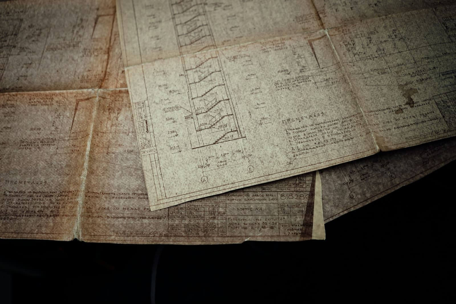 Old paper engineering drawings, worn and folded, on a table