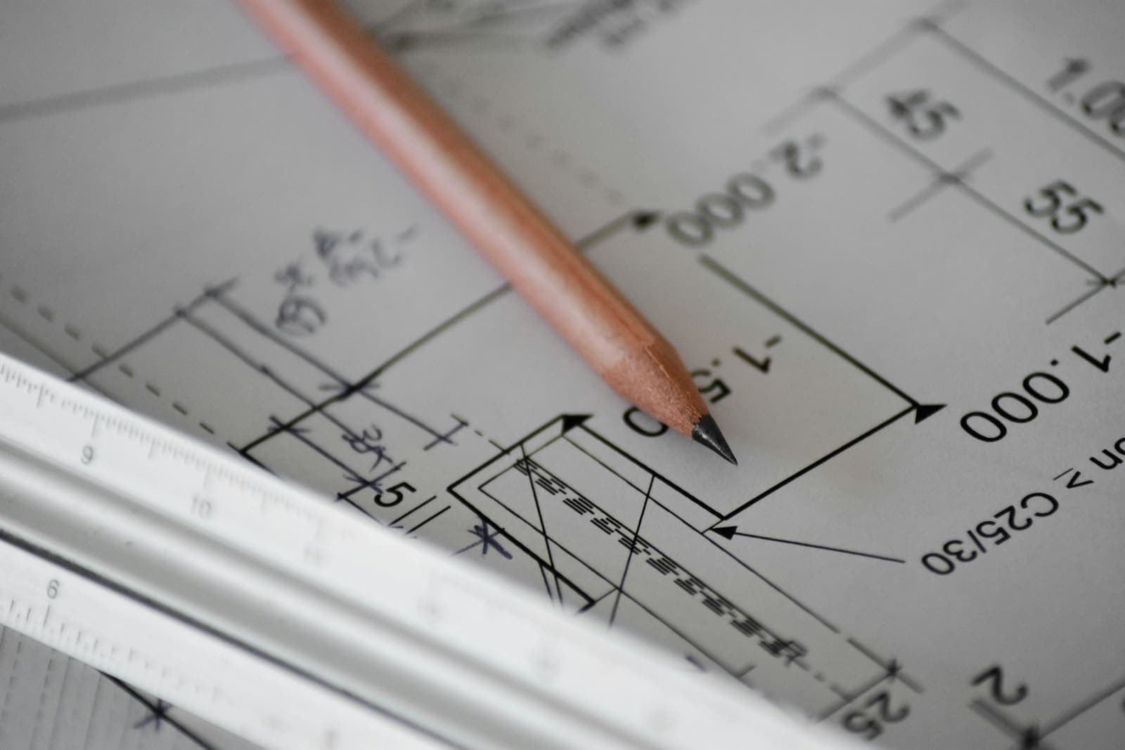 A pencil resting on a dimensioned engineering drawing